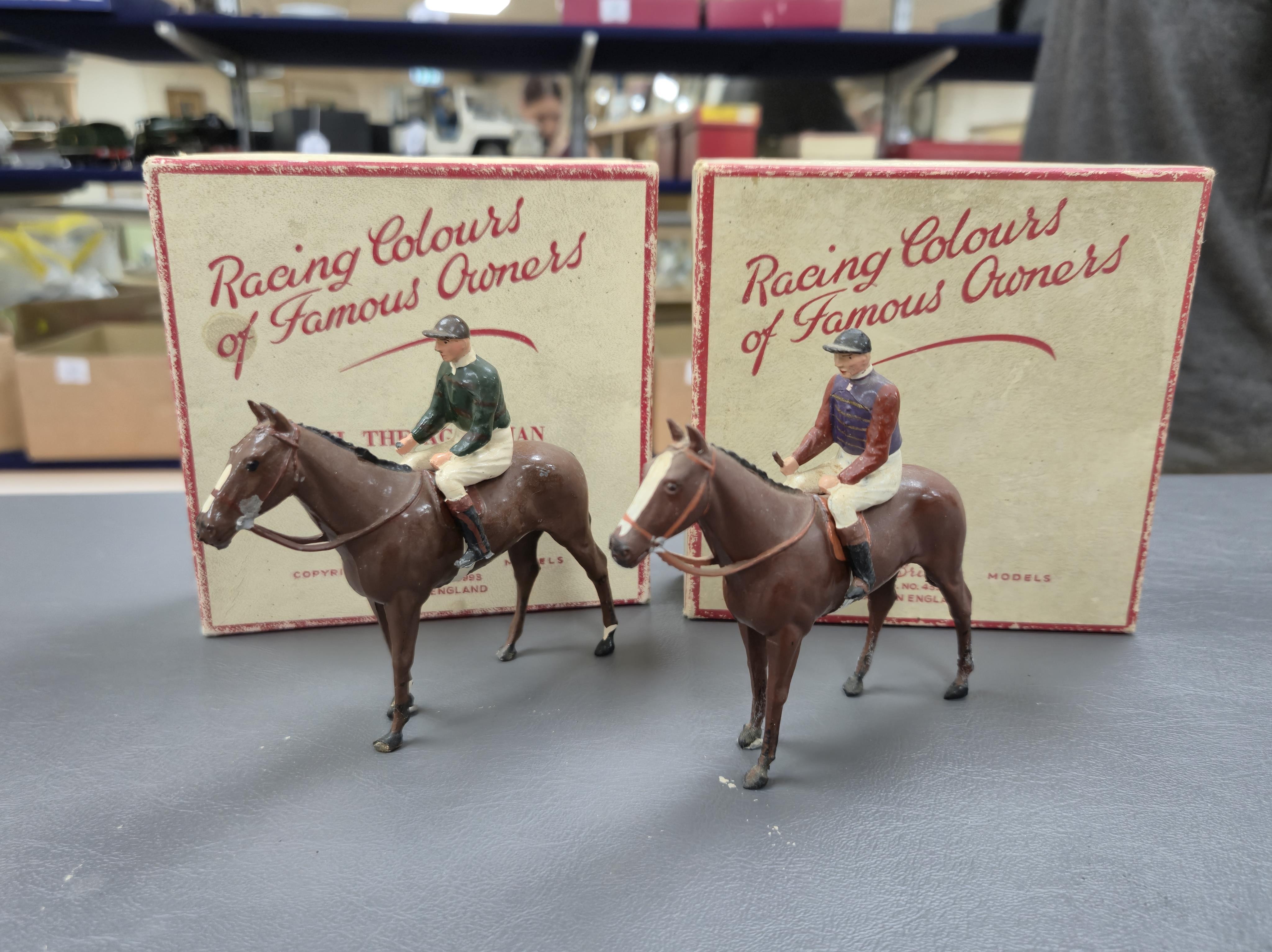 Two boxed Britains Racing Colours of Famous Owners series lead mounted figures; H.M. The Queen - rider in purple and brown jersey with gold frogging on a brown horse, and H.H. The Aga Khan - rider in dark green jersey on